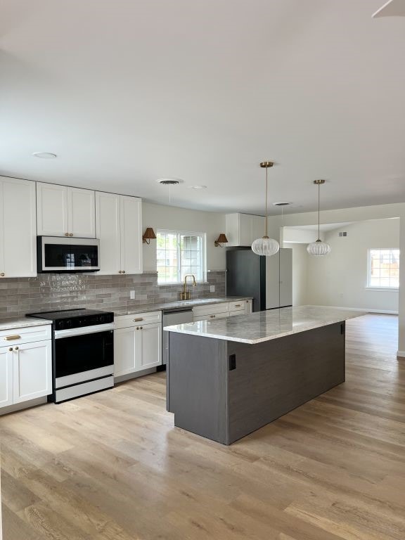 kitchen featuring light wood finished floors, appliances with stainless steel finishes, a center island, and white cabinetry