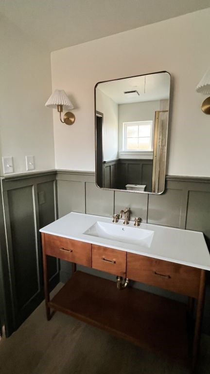 bathroom featuring a wainscoted wall, wood finished floors, and vanity