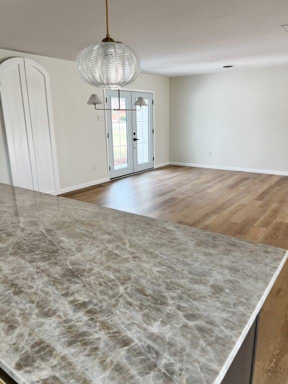 empty room with french doors, baseboards, and wood finished floors