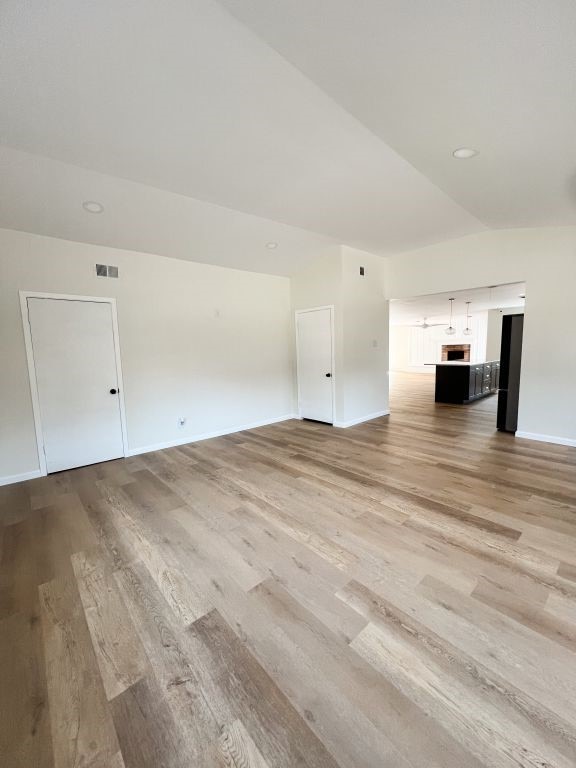 unfurnished living room with visible vents, light wood-type flooring, and baseboards