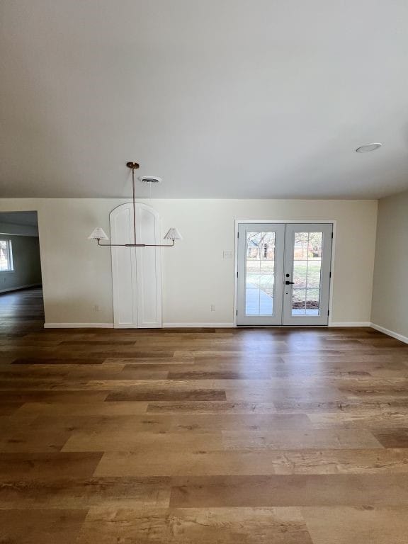 empty room featuring french doors, baseboards, and wood finished floors