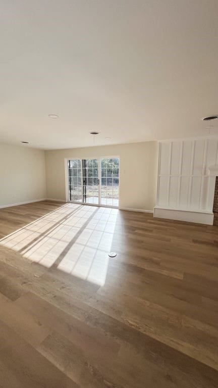 empty room with wood finished floors, visible vents, and baseboards