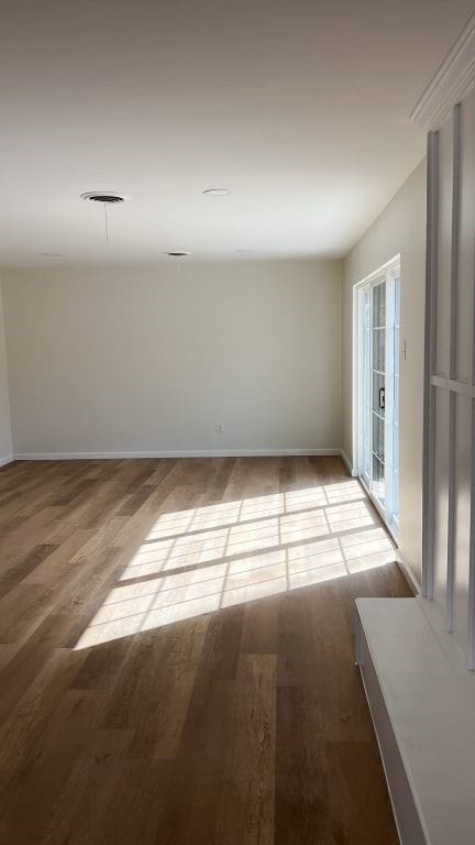 spare room with baseboards and wood finished floors