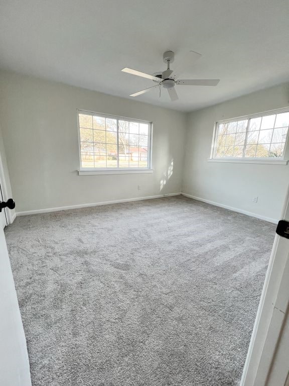 carpeted empty room featuring plenty of natural light, a ceiling fan, and baseboards