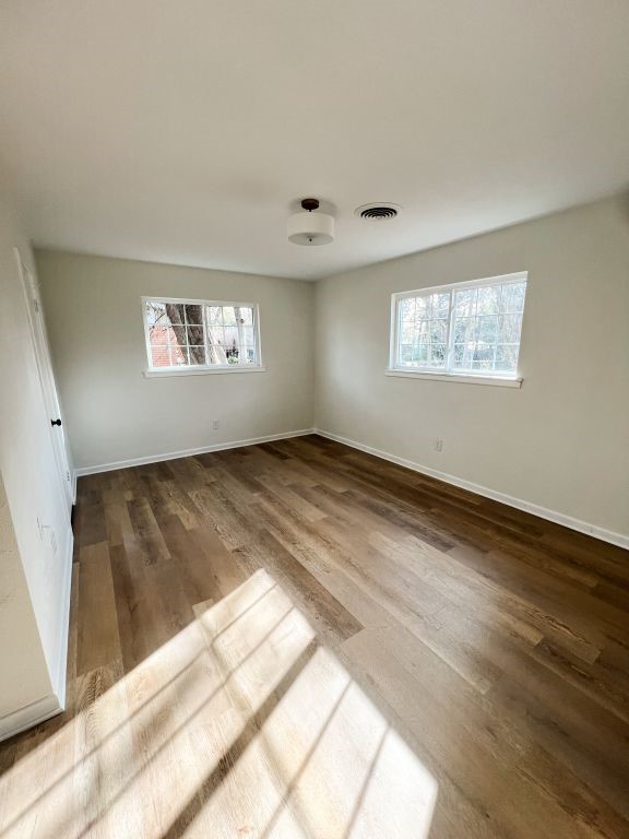 empty room with visible vents, baseboards, and wood finished floors