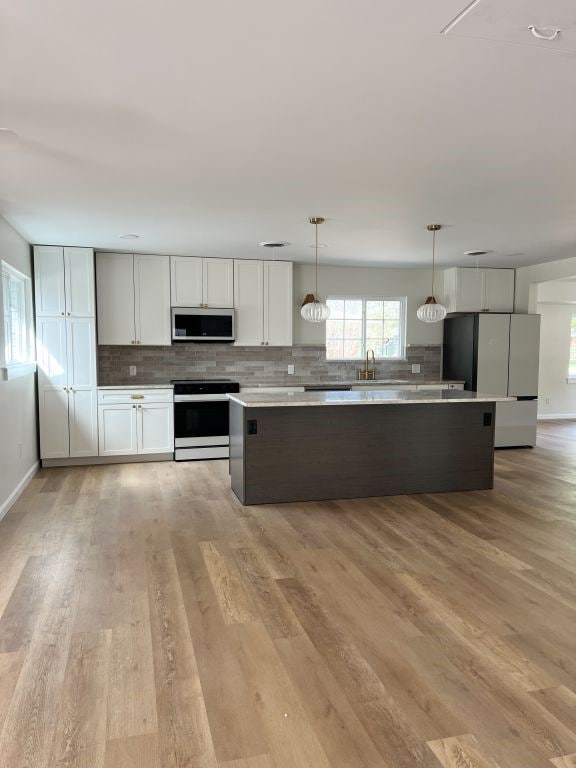 kitchen with freestanding refrigerator, electric range oven, decorative backsplash, stainless steel microwave, and a center island