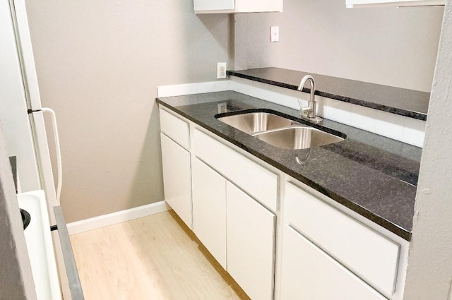 kitchen featuring white cabinetry, sink, dark stone countertops, white fridge, and light wood-type flooring