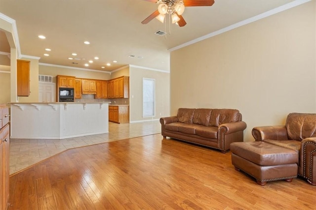 living room with ornamental molding, ceiling fan, and light hardwood / wood-style floors