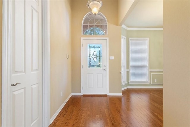 entrance foyer featuring crown molding, a towering ceiling, wood-type flooring, and a chandelier