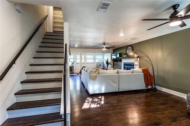 living room featuring a textured ceiling, ceiling fan, and dark hardwood / wood-style floors