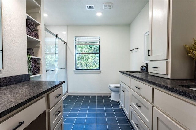 bathroom featuring tile patterned floors, vanity, toilet, and a shower with shower door