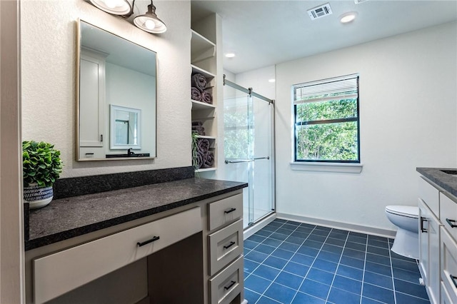 bathroom featuring tile patterned flooring, vanity, toilet, and walk in shower