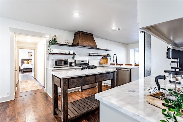 kitchen with backsplash, sink, dark hardwood / wood-style floors, appliances with stainless steel finishes, and kitchen peninsula