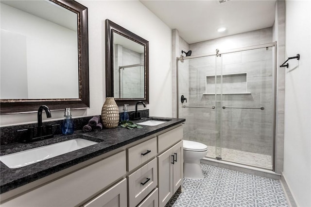 bathroom featuring tile patterned floors, vanity, toilet, and a shower with shower door