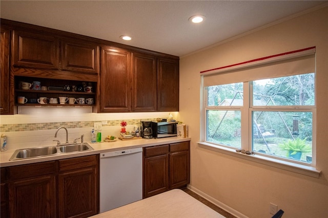 kitchen featuring sink, tasteful backsplash, white dishwasher, dark brown cabinets, and ornamental molding