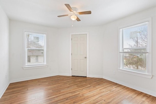 spare room with ceiling fan, light wood-type flooring, and a wealth of natural light