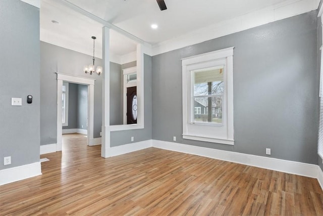 unfurnished room with ceiling fan with notable chandelier and light hardwood / wood-style flooring