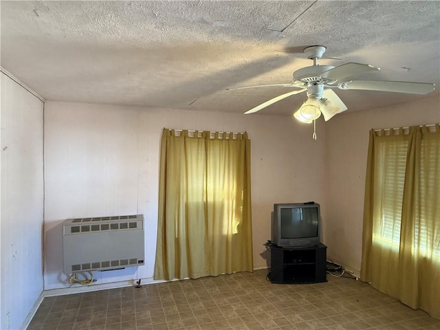 interior space featuring ceiling fan, heating unit, and a textured ceiling