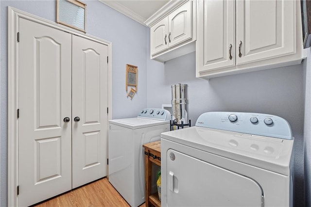 laundry room with cabinets, ornamental molding, independent washer and dryer, and light hardwood / wood-style flooring