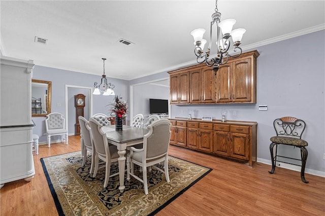 dining space with crown molding, a notable chandelier, and light hardwood / wood-style floors