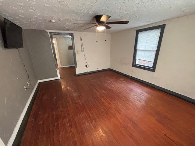 spare room featuring wood finished floors, baseboards, and a textured ceiling