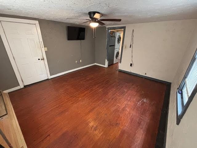 basement with stacked washer and dryer, a ceiling fan, a textured ceiling, wood finished floors, and baseboards