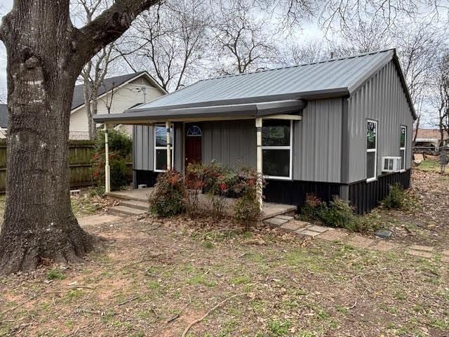 view of front of house with board and batten siding, covered porch, and metal roof