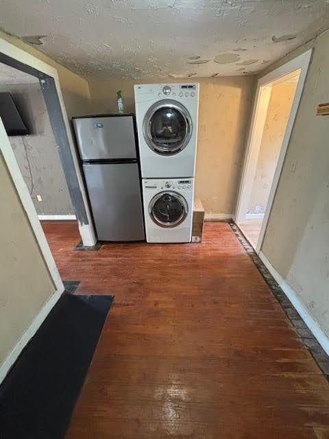 laundry area featuring baseboards, wood finished floors, and stacked washer / dryer