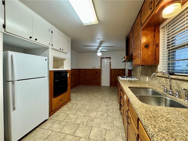 kitchen with ceiling fan, sink, wood walls, white appliances, and exhaust hood