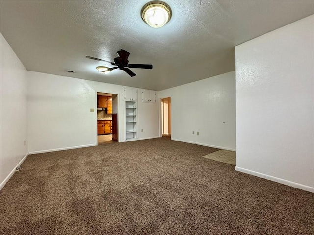 unfurnished living room featuring carpet flooring, built in shelves, ceiling fan, and a textured ceiling