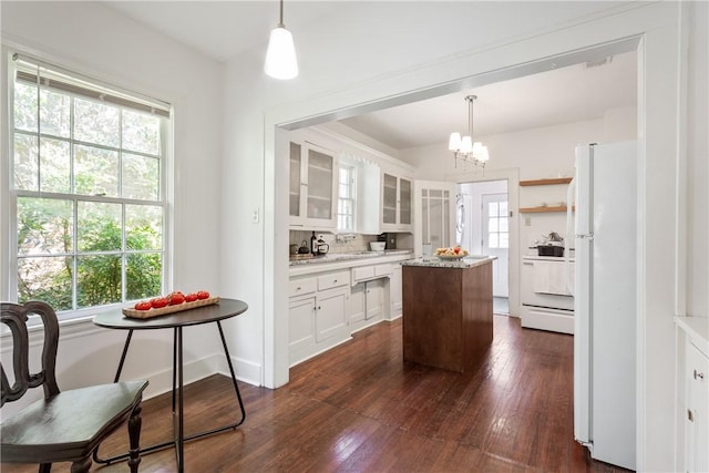 kitchen featuring stove, a center island, dark hardwood / wood-style floors, white cabinetry, and hanging light fixtures