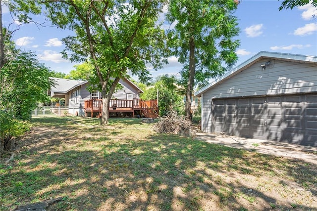 view of yard with a wooden deck, an outbuilding, and a garage