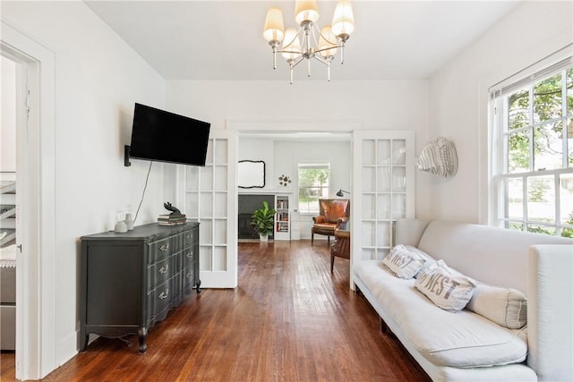 living room with a chandelier, dark wood-type flooring, a healthy amount of sunlight, and french doors