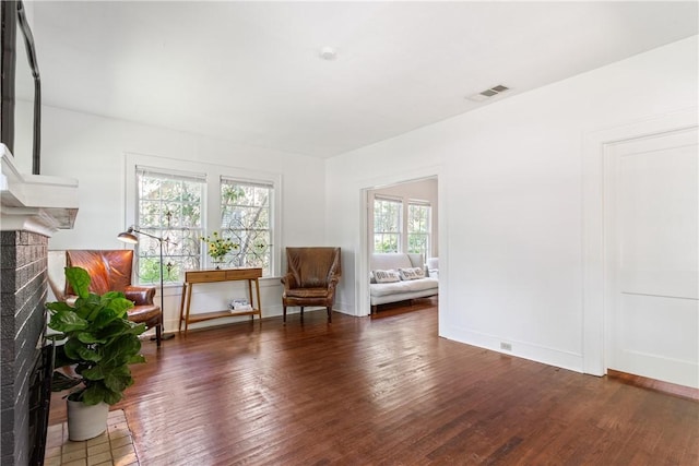 unfurnished room featuring dark hardwood / wood-style flooring and a brick fireplace