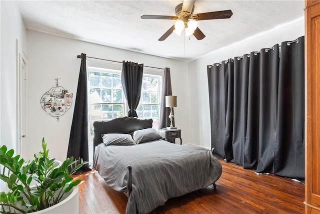 bedroom featuring a textured ceiling, ceiling fan, and dark hardwood / wood-style floors