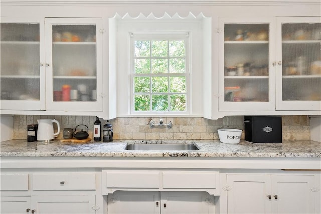 interior details featuring white cabinets, tasteful backsplash, and sink