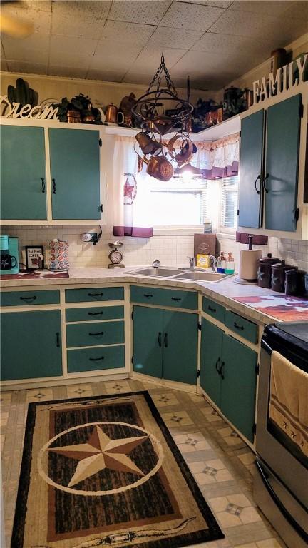 kitchen featuring a drop ceiling, black electric range oven, green cabinets, sink, and tasteful backsplash