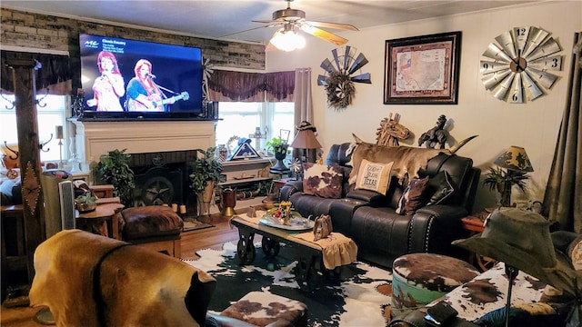 living room with ceiling fan, brick wall, and hardwood / wood-style flooring