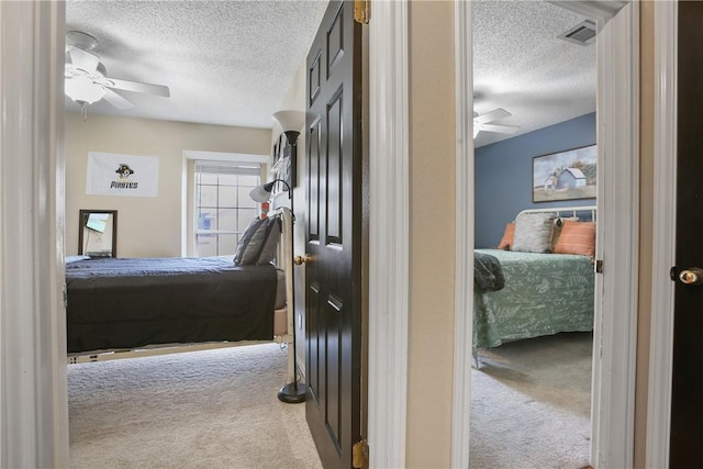 carpeted bedroom with ceiling fan and a textured ceiling