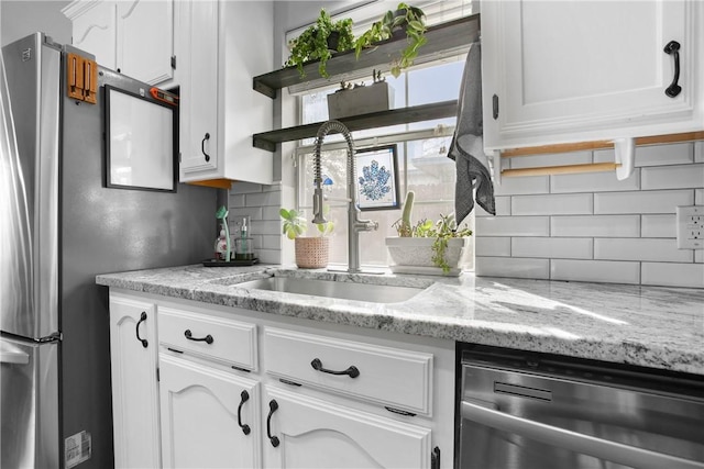 kitchen with tasteful backsplash, dishwasher, sink, and white cabinetry