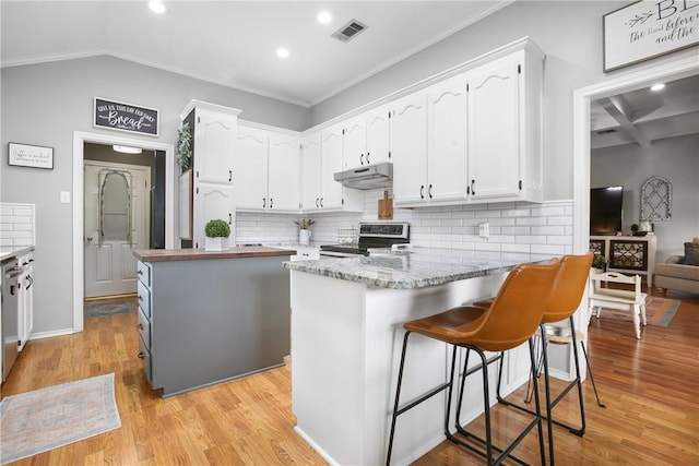 kitchen featuring white cabinetry, backsplash, stainless steel electric stove, and light hardwood / wood-style floors