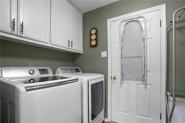 laundry area with cabinets, washing machine and clothes dryer, and a textured ceiling