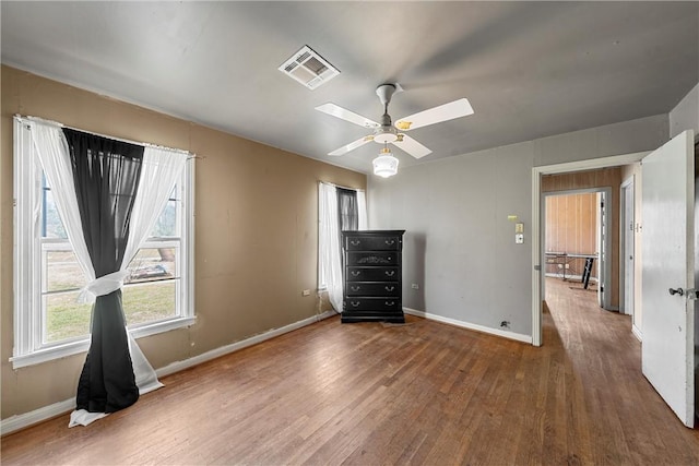 unfurnished bedroom with ceiling fan, wood finished floors, visible vents, and baseboards