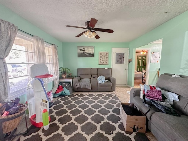 tiled living room featuring ceiling fan and a textured ceiling