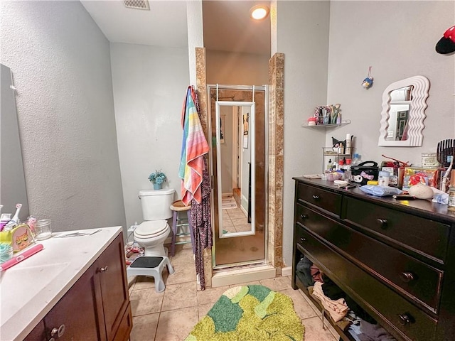 bathroom featuring tile patterned flooring, vanity, toilet, and an enclosed shower