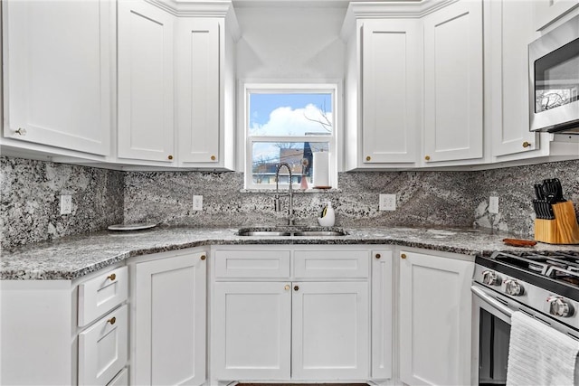 kitchen with stainless steel appliances, backsplash, a sink, and white cabinetry