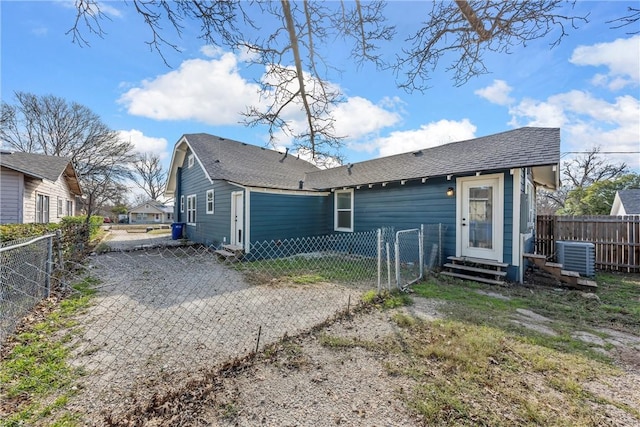 back of property with driveway, entry steps, a shingled roof, fence, and central air condition unit