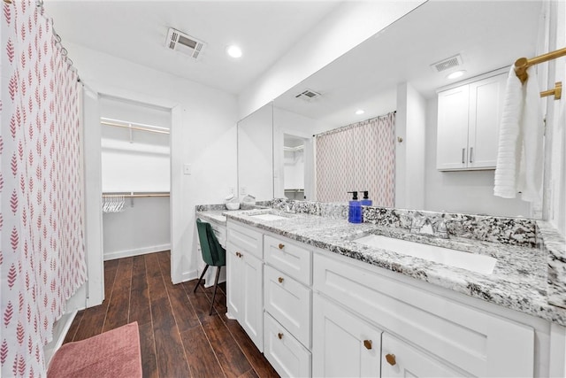 full bath featuring double vanity, visible vents, a sink, and wood finished floors