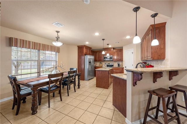 kitchen featuring decorative backsplash, a center island, light stone counters, kitchen peninsula, and stainless steel appliances