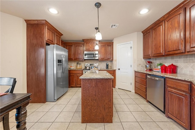 kitchen with stainless steel appliances, light stone countertops, a center island, and light tile patterned floors